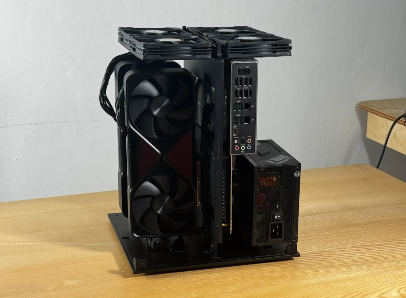 Open dual-GPU professional workstation concept with two large vertically mounted cards, central cooling fan, motherboard ports, and a compact power supply.